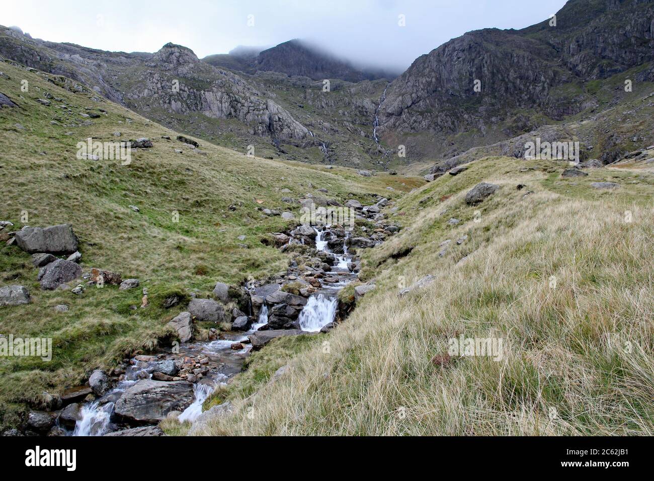 Le ruisseau de montagne mène vers Clogwyn avec Snowdon entouré de nuages, parc national de Snowdonia, au nord du pays de Galles Banque D'Images