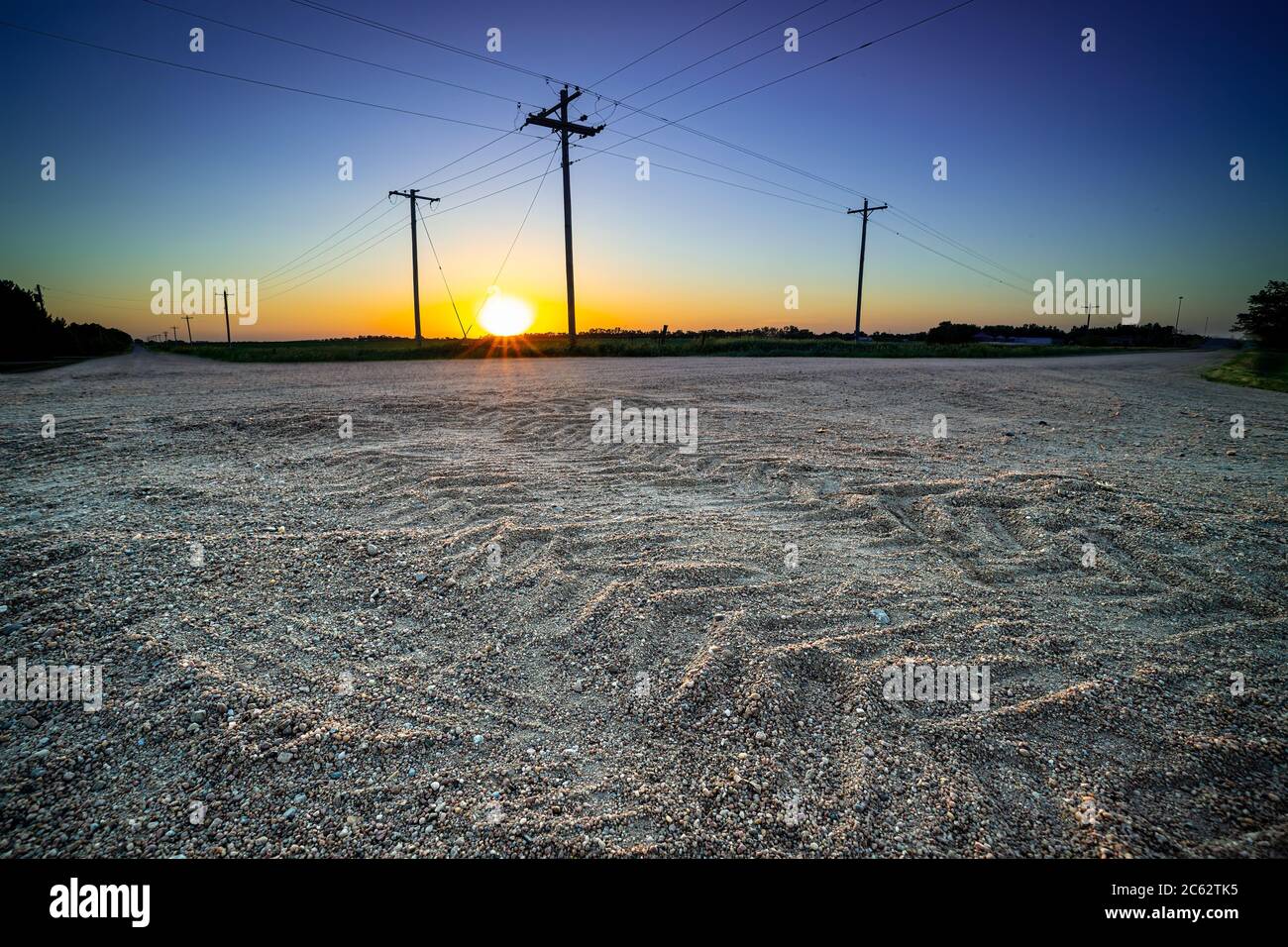 Les traces de pneus de tracteur sont détaillées avec des poteaux téléphoniques et le soleil au coucher du soleil, Donifan, Nebraska, États-Unis Banque D'Images