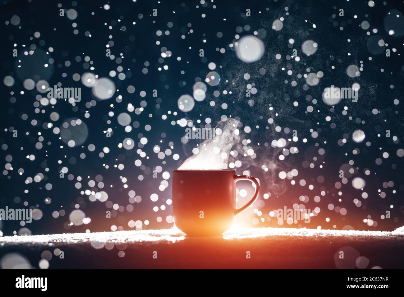 tasse de café chaud ou de thé illuminée sur fond enneigé la nuit Banque D'Images