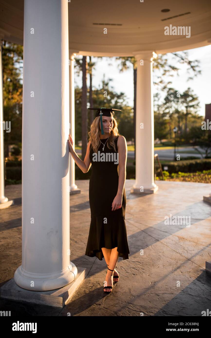 étudiant collégial dans la cour posant près d'une colonne avec chapeau de graduation Banque D'Images