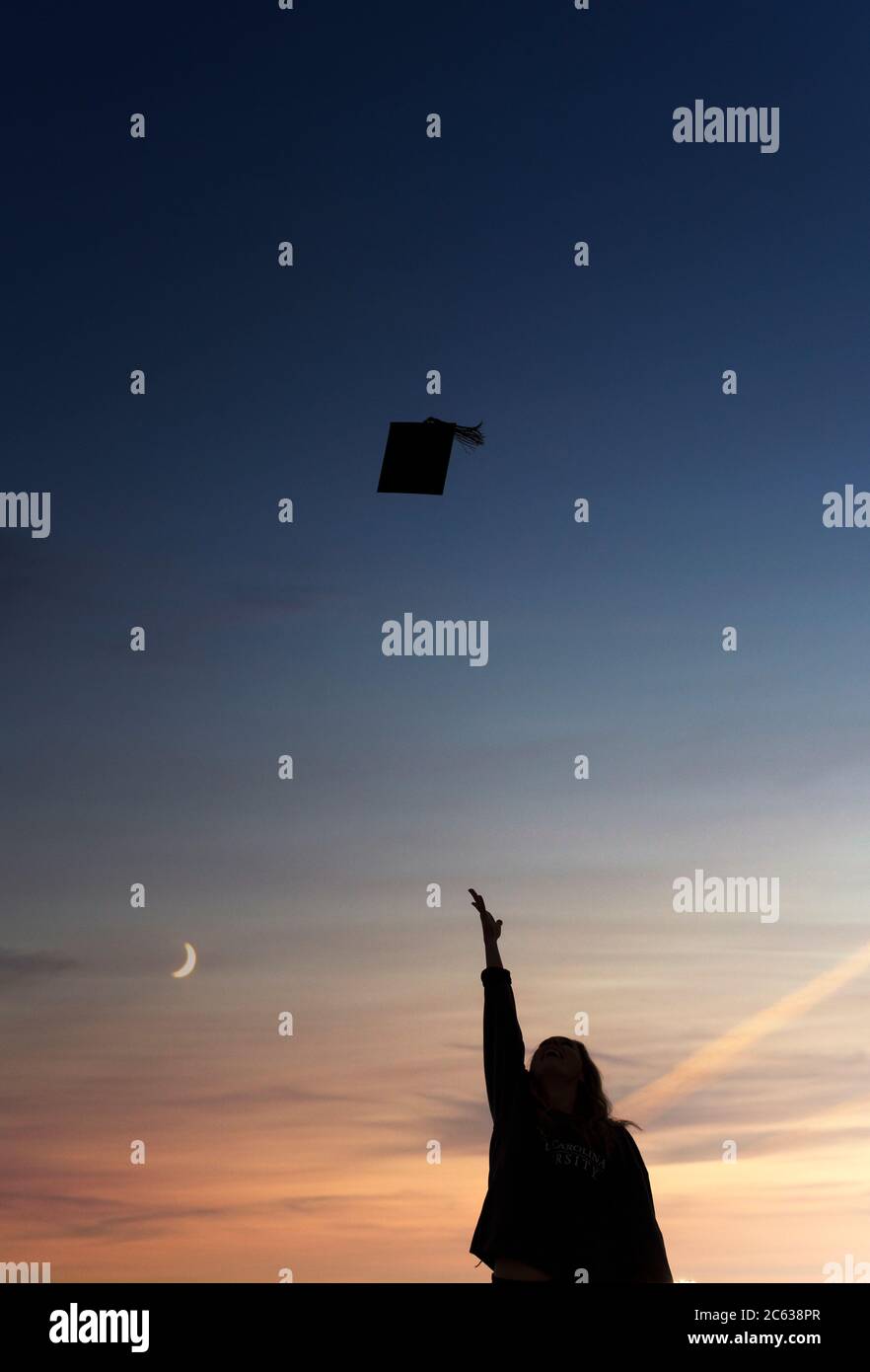 Silhouette d'un étudiant jetant une casquette de fin d'études dans l'air Banque D'Images
