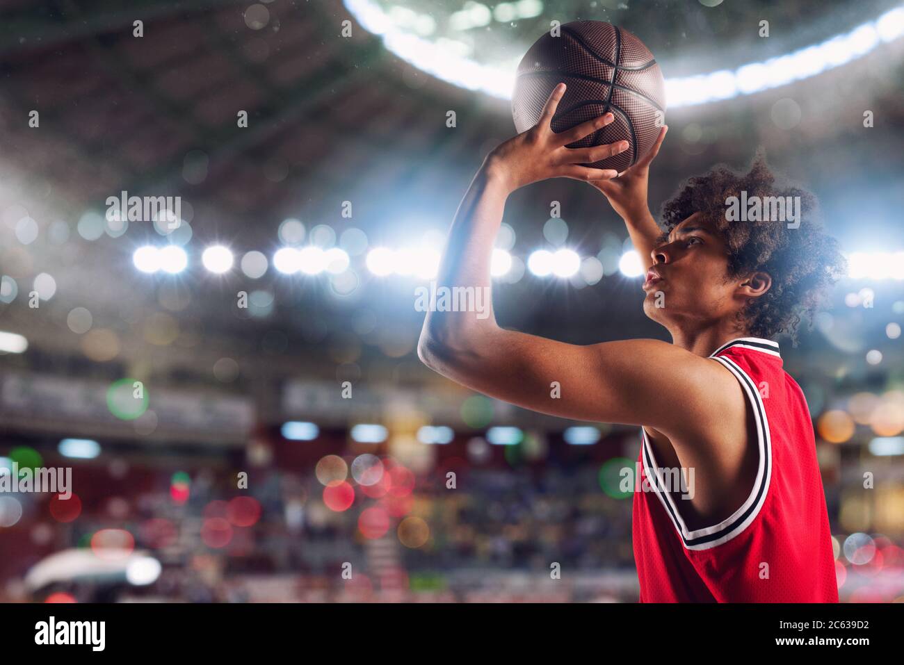 Un joueur de basket-ball jette le ballon dans le panier du stade plein de spectateurs. Banque D'Images