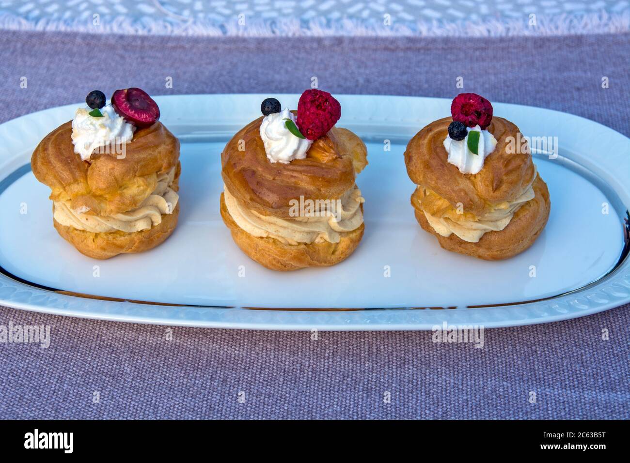 Trois beignets de princesse sur une assiette avec des décorations de fruits doux sur eux. Banque D'Images