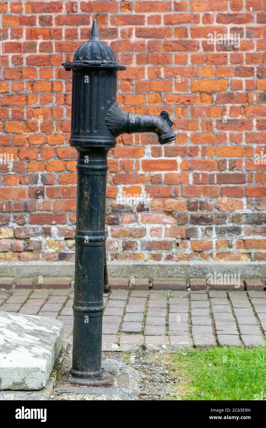 Pompe à eau en fonte antique contre un mur de briques rouges arrière Banque D'Images