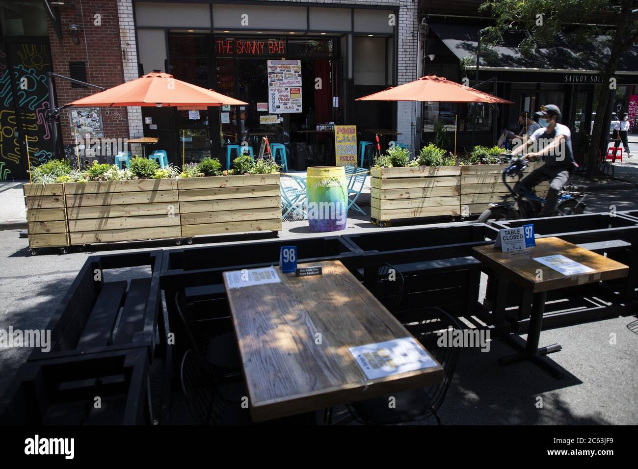 New York, États-Unis. 6 juillet 2020. Un cycliste passe devant la salle à manger extérieure des restaurants de Manhattan de New York City, aux États-Unis, le 6 juillet 2020. La ville de New York, qui fut l'épicentre de la crise de la COVID-19 aux États-Unis, est entrée dans la troisième phase de réouverture lundi sans reprendre les repas à l'intérieur. Les services de soins personnels, tels que les salons d'ongles et les salons de massage, sont autorisés à rouvrir après presque quatre mois de fermeture. Crédit : Wang Ying/Xinhua/Alay Live News Banque D'Images