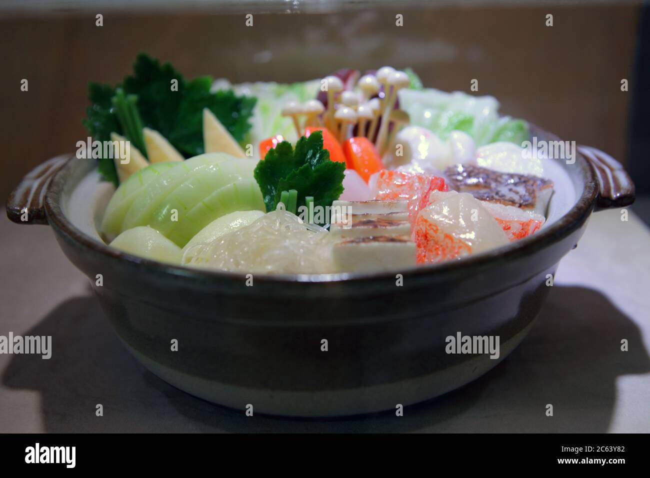 Sukiyaki ou nabe de style japonais. Il y a beaucoup de fruits de mer et de légumes dans un pot en argile. Banque D'Images