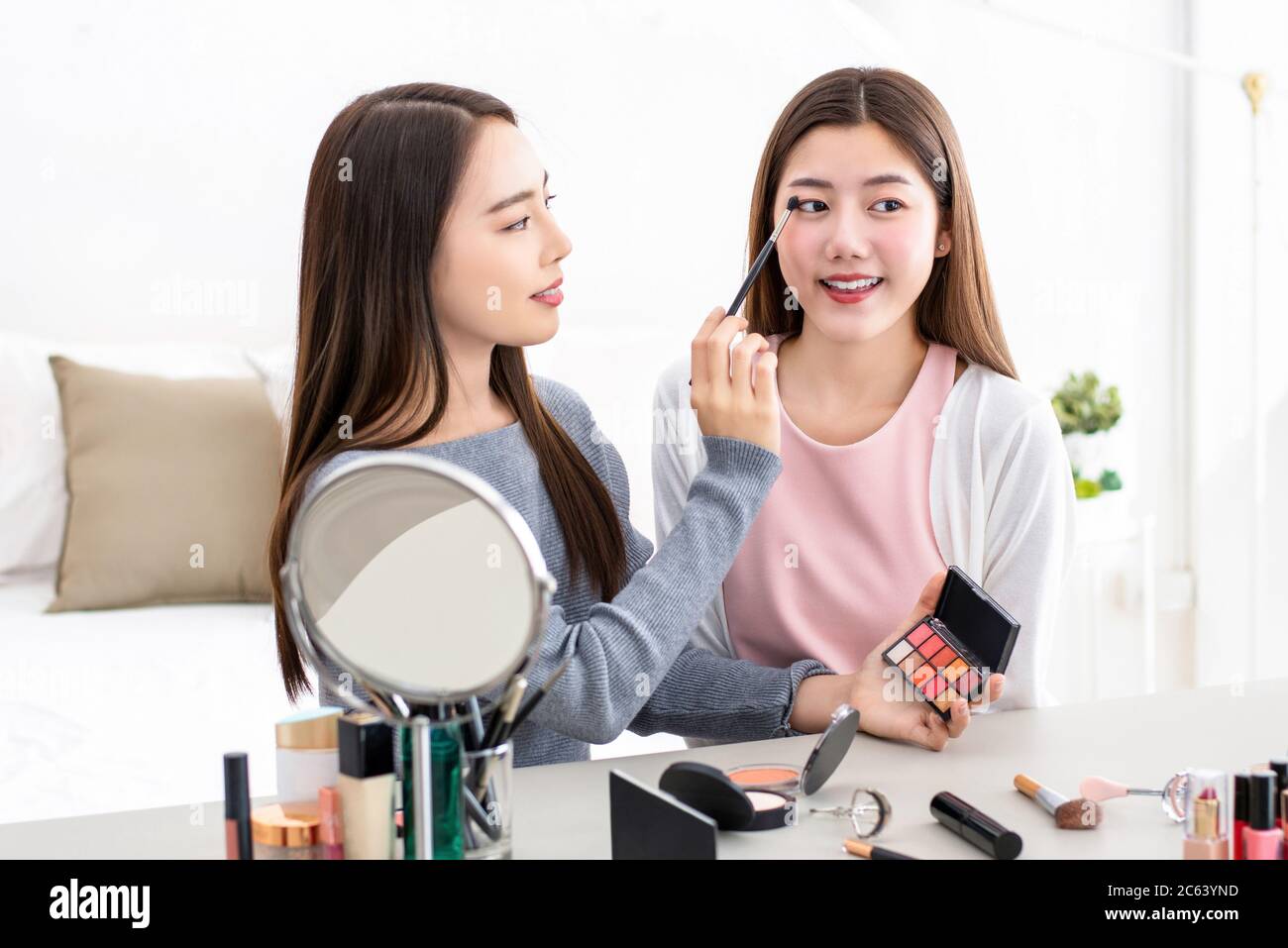 Belle femme asiatique de beauté vlogger faisant la démonstration cosmétique de maquillage avec son ami à la maison Banque D'Images