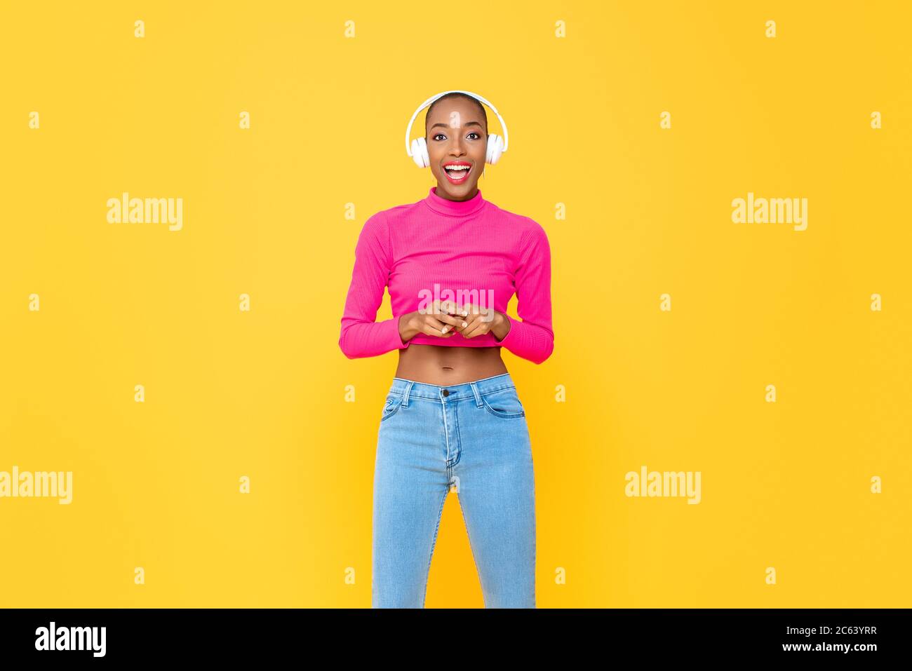 Femme afro-américaine à la mode avec casque souriant sur fond jaune coloré isolé studio Banque D'Images