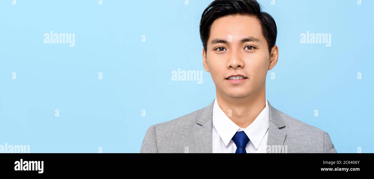 Portrait d'un jeune homme asiatique beau en costume d'affaires formel isolé sur fond de bannière bleu clair avec espace de copie Banque D'Images