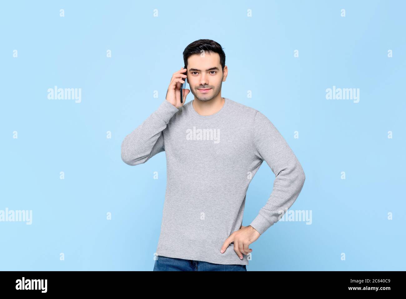 Portrait de handsosme homme caucasien appelant sur téléphone mobile dans isolé bleu clair bakground studio Banque D'Images