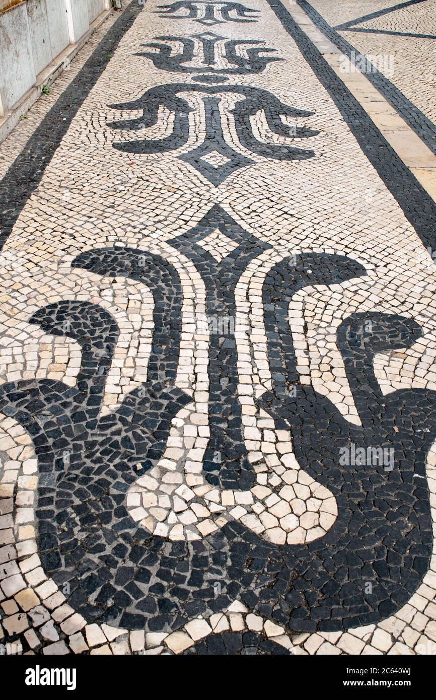 Les pavés portugais noirs et blancs, appelés calcada, sont disposés en configuration traditionnelle sur un trottoir à Lisbonne, au Portugal. Banque D'Images
