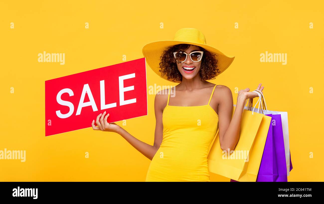 Surprise tendance cheveux curly femme portant des sacs de shopping avec signe de vente rouge sur fond jaune Banque D'Images