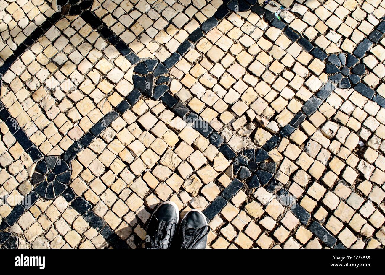 Une paire de chaussures noires se trouve sur le calcada noir et blanc, pavés portugais en mosaïque, sur la Rua Garrett à Lisbonne. Banque D'Images