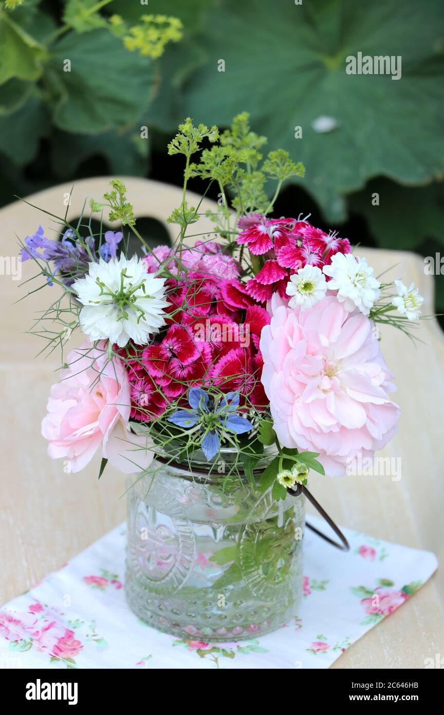 petit bouquet de roses roses et fleurs d'été dans vase en verre comme décoration Banque D'Images