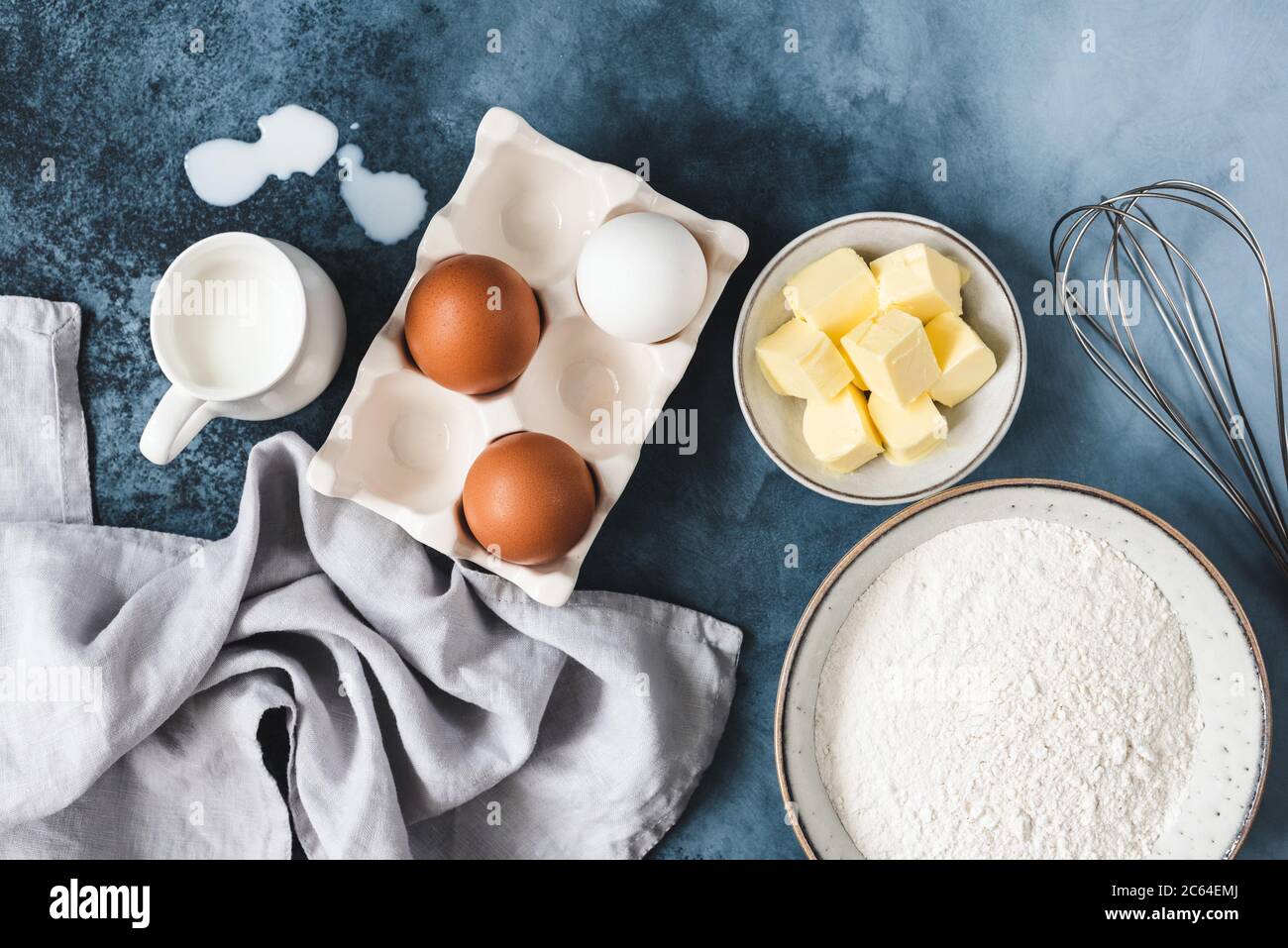 Ingrédients pour cuire sur fond bleu. Œufs, beurre en cubes, farine de lait et whisky. Vue de dessus Banque D'Images