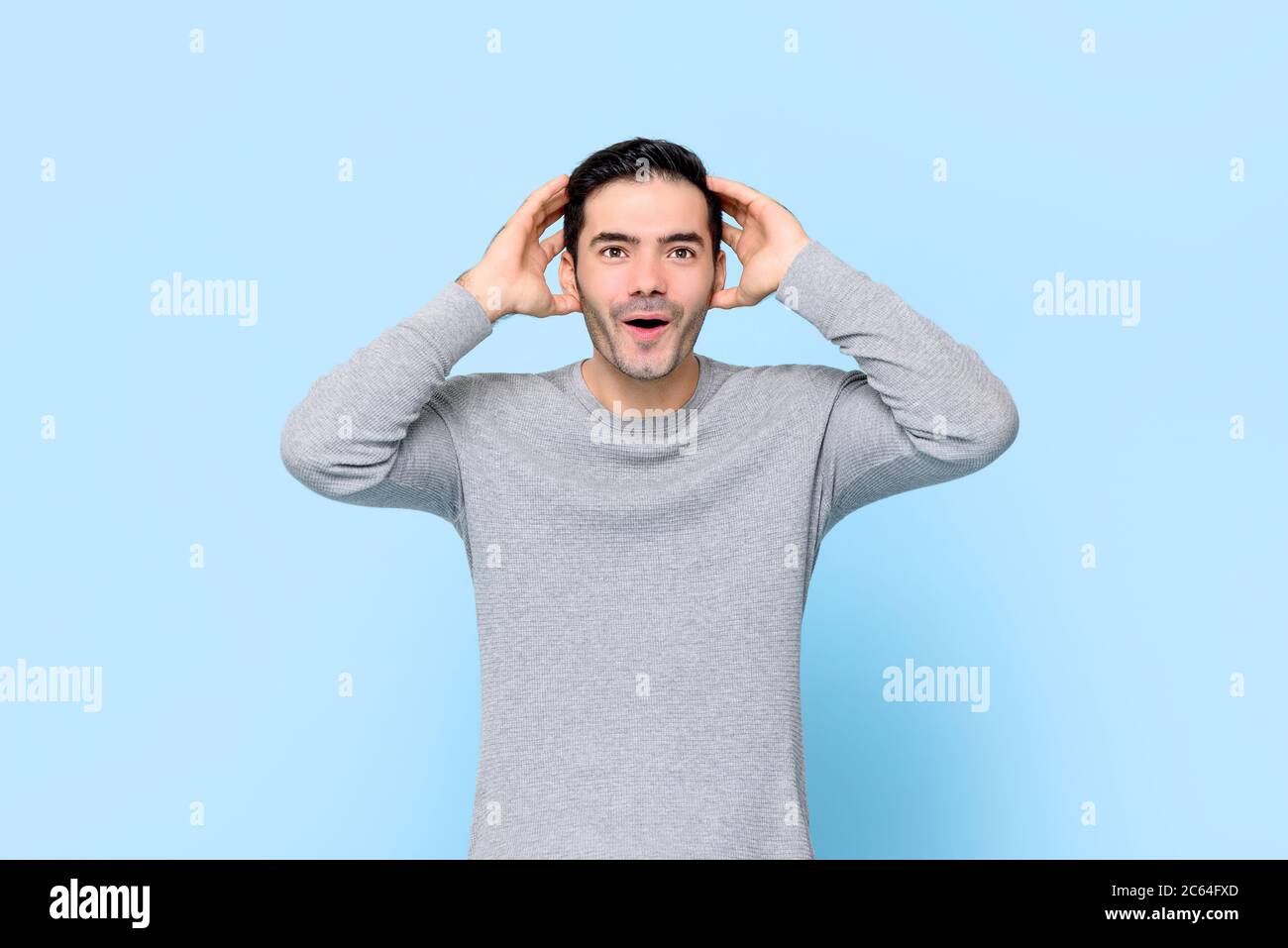 Choqué, beau homme caucasien, qui resserre la tête et l'isole sur fond bleu clair Banque D'Images