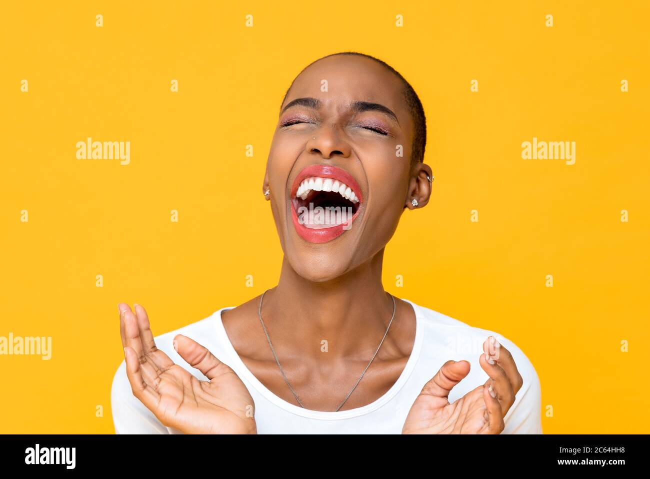 Gros plan portrait d'une jeune femme afro-américaine heureuse qui rit à voix haute avec les deux mains dans le clapping gestuel isolé studio jaune fond Banque D'Images
