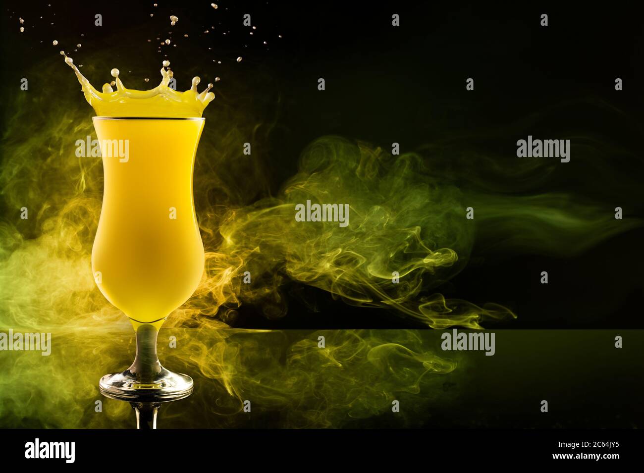 cocktail jaune éclaboussant et tourbillons de fumée sur fond noir Banque D'Images