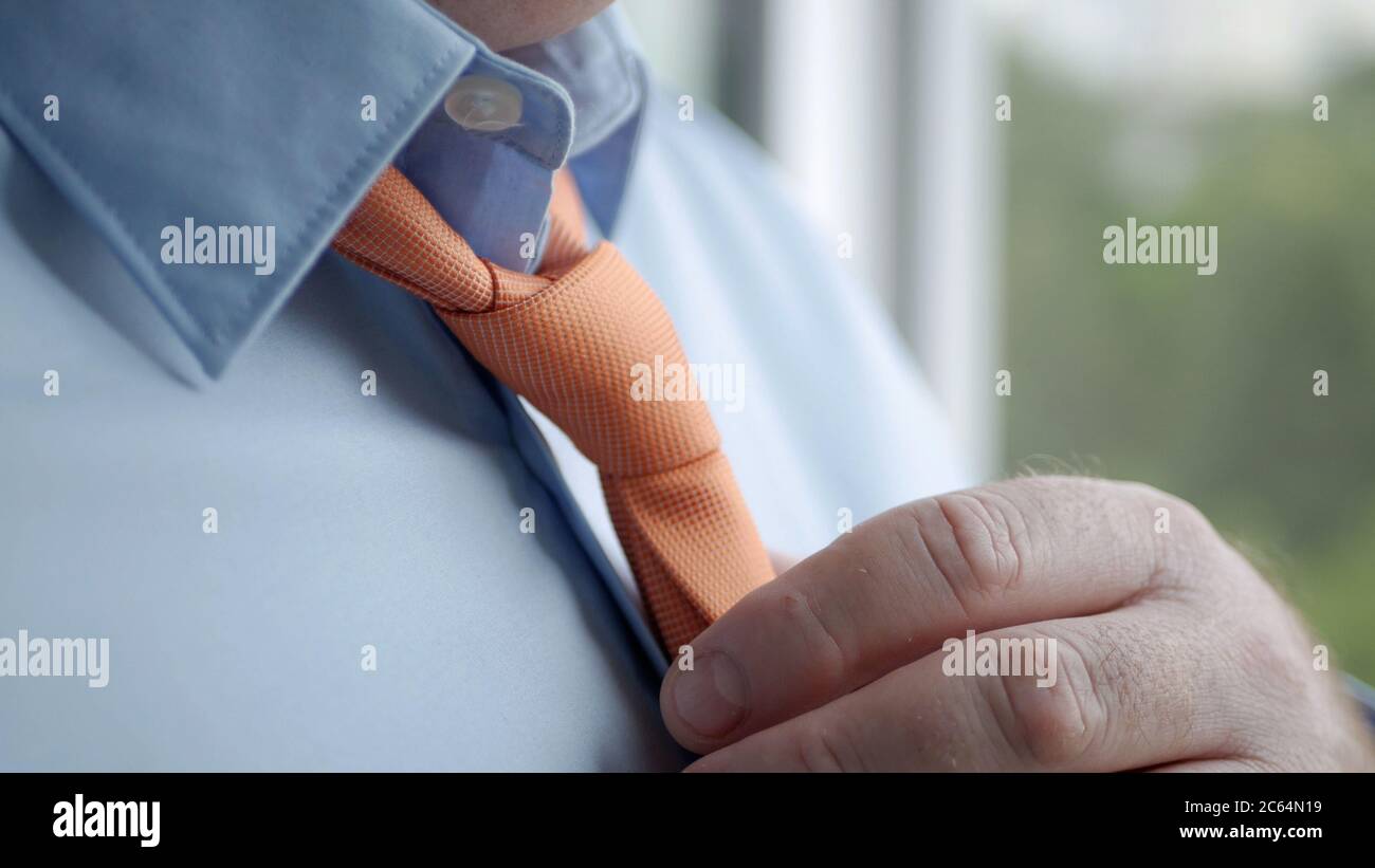 Élégante image homme d'affaires portant une chemise bleue et faisant un  nœud à une cravate orange Photo Stock - Alamy