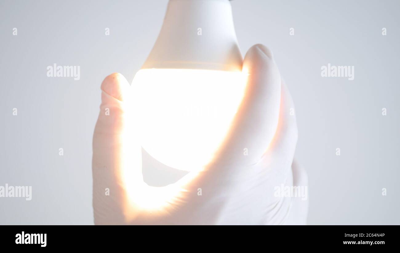 La main d'un électricien fait tourner une ampoule LED dans la prise