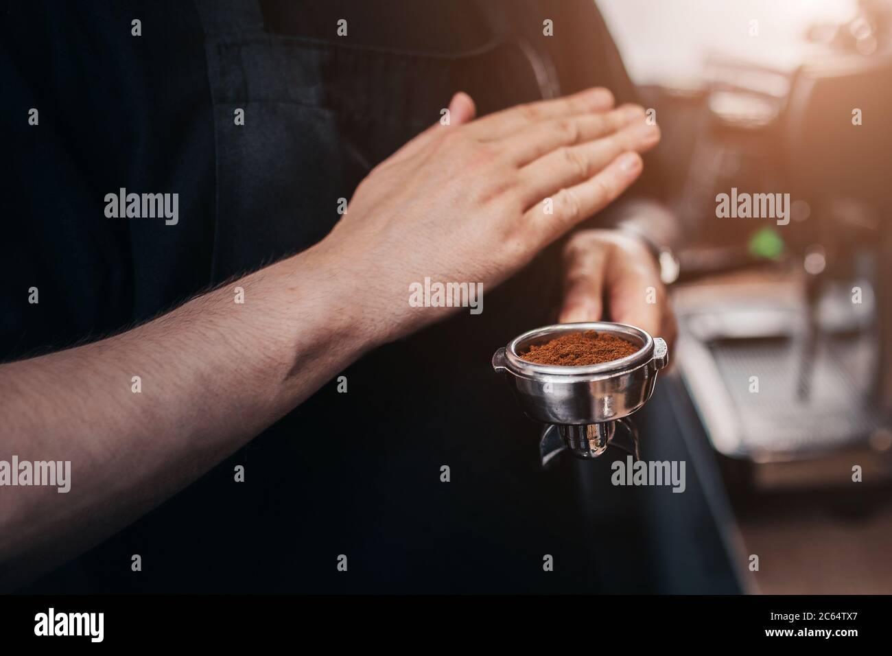 Le barista professionnel prépare et condense le café moulu dans le support en effectuant de brefs mouvements de la main Banque D'Images