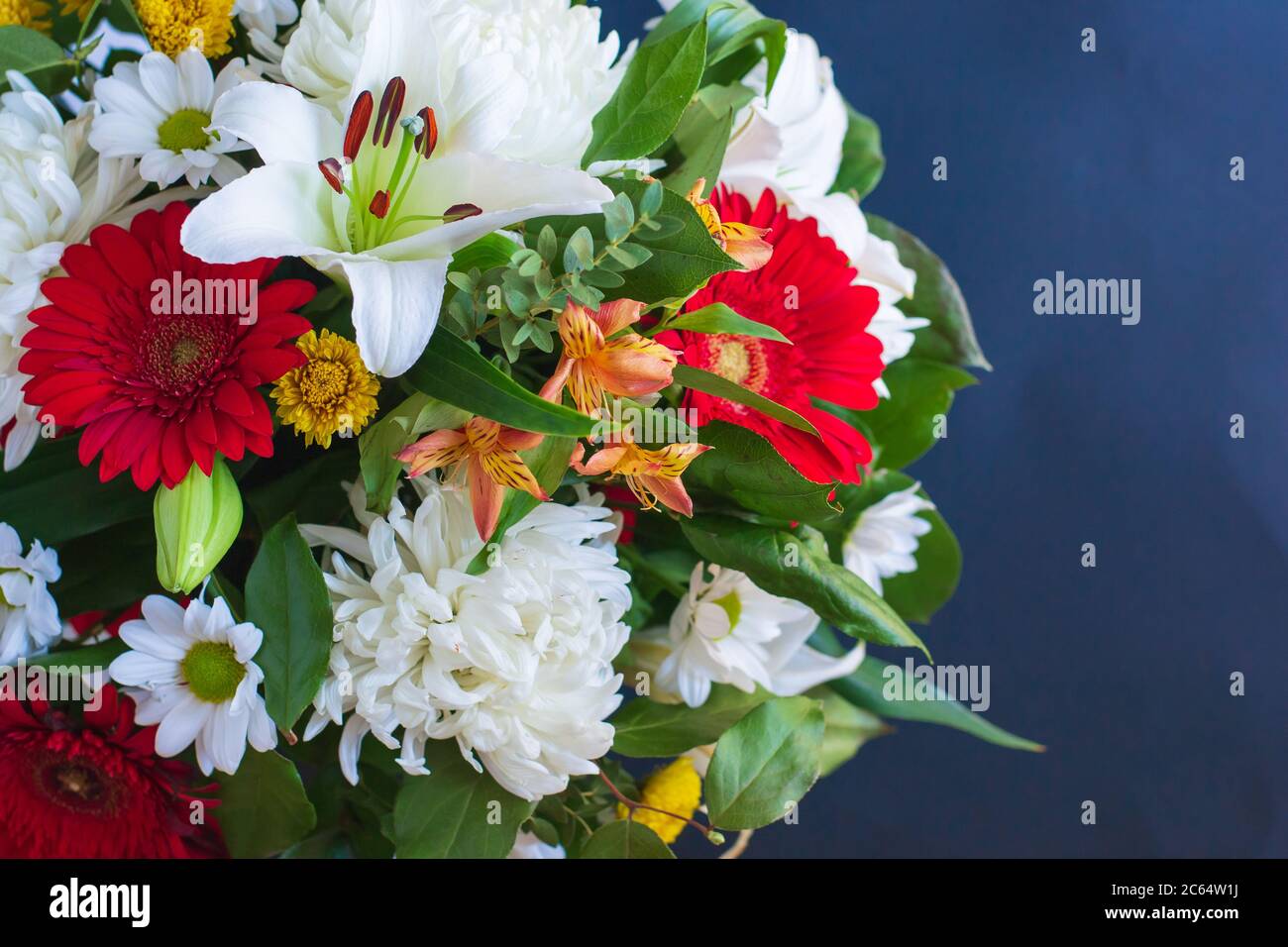 Bouquet lumineux de feuilles vert lys gerbera chrysanthème sur fond sombre gros plan.fond floral festif avec espace pour le texte pour toutes les occasions Banque D'Images