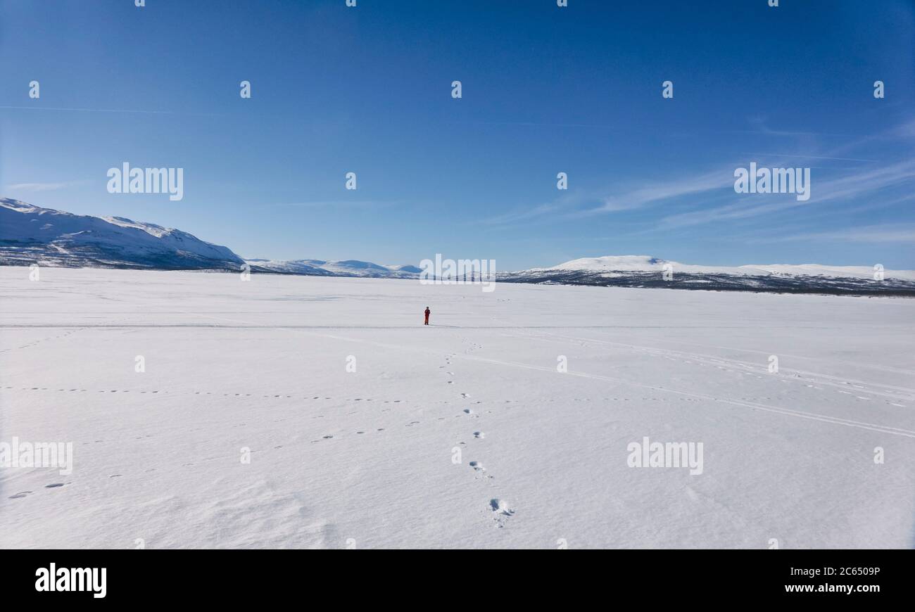 Vue lointaine d'un garçon marchant sur un lac gelé à Vasterbotten LAN, Suède. Banque D'Images