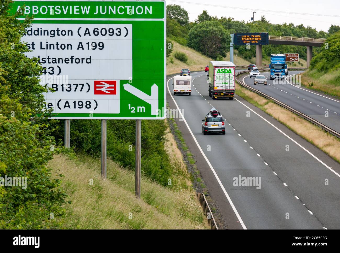 East Lothian, Écosse, Royaume-Uni, 7 juillet 2020. Nouveau message Covid-19 sur le statif A1 : la troisième version du message pandémique apparaît sur le statif au-dessus de la tête, près de Haddington, qui indique « local Travel restrictions Stay Safe », alors que l'Écosse se réduit à la phase 3 prévue la semaine prochaine. La circulation sur la route à deux voies est beaucoup plus lourde que ce qui a été apparent ces derniers mois Banque D'Images