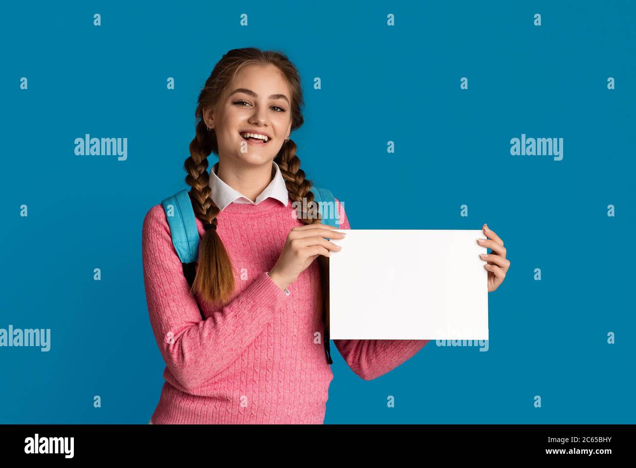 Fille souriante école fille tient la feuille blanche avec l'espace vide Banque D'Images