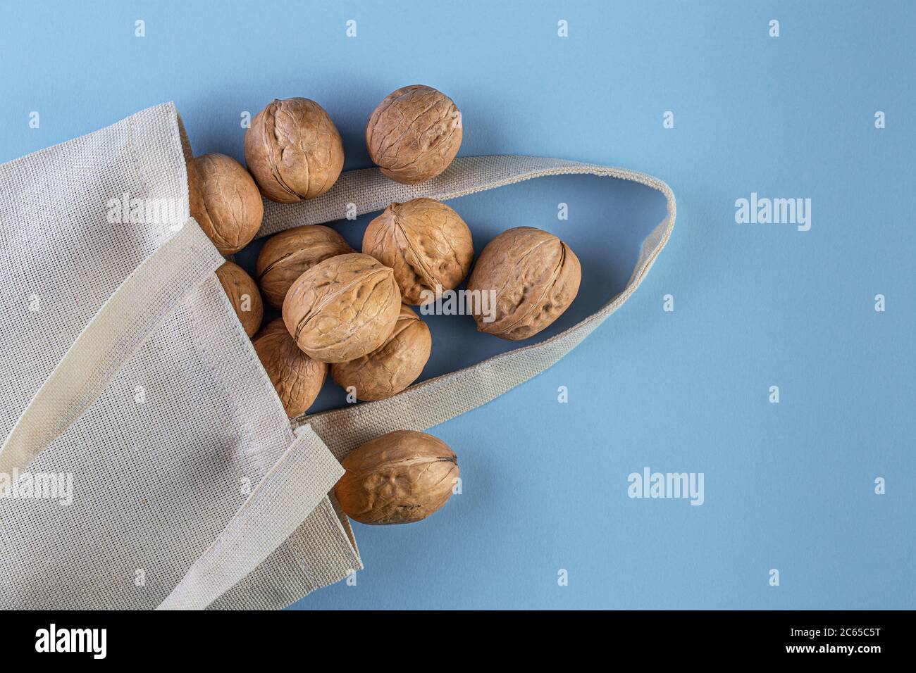 Noix en sachet de coton sur fond bleu. Concept alimentaire naturel biologique sain et végétalien. Flat lay, vue de dessus avec espace de copie Banque D'Images