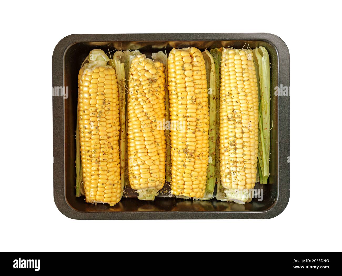 Plaque de cuisson noire isolée avec épis de maïs épicés, feuilles sur fond blanc Banque D'Images
