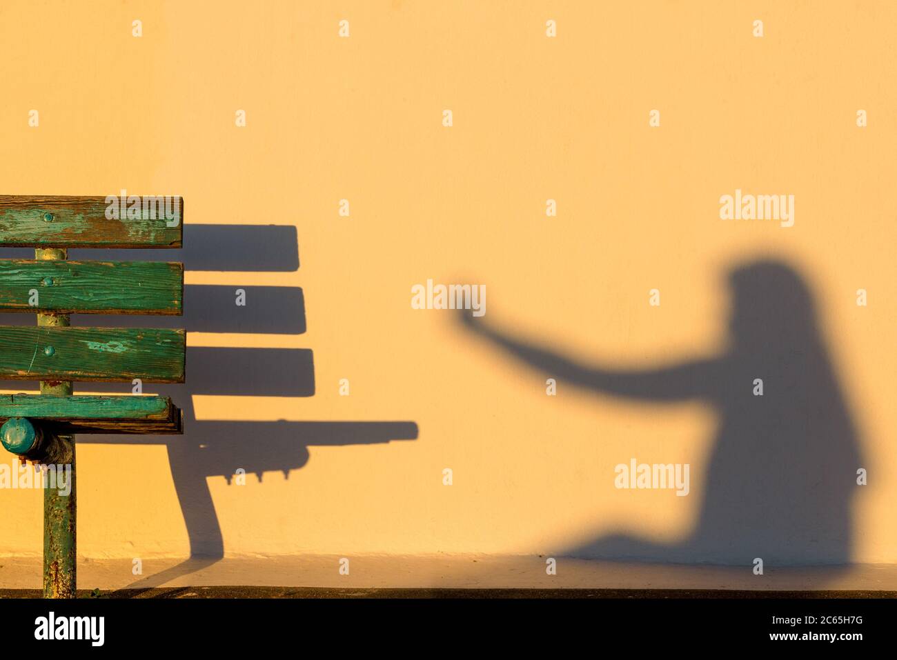 Ombre d'un selfie sur un mur jaune et d'un banc au premier plan avec une faible lumière à Santorin, Grèce Banque D'Images