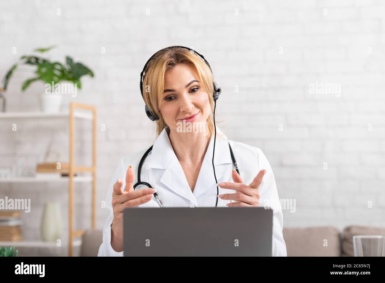 Consultant en ligne au centre médical. Médecin sympathique gesalin, regardant l'ordinateur portable, communiquant avec le patient Banque D'Images