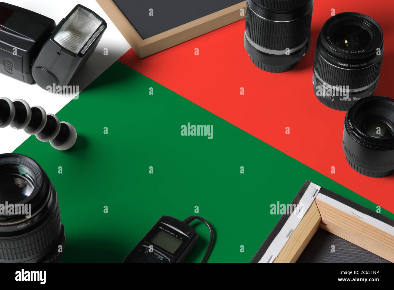 Drapeau national de Madagascar avec vue de dessus de l'équipement et des outils de photographe personnel sur table en bois blanc, espace de copie. Banque D'Images