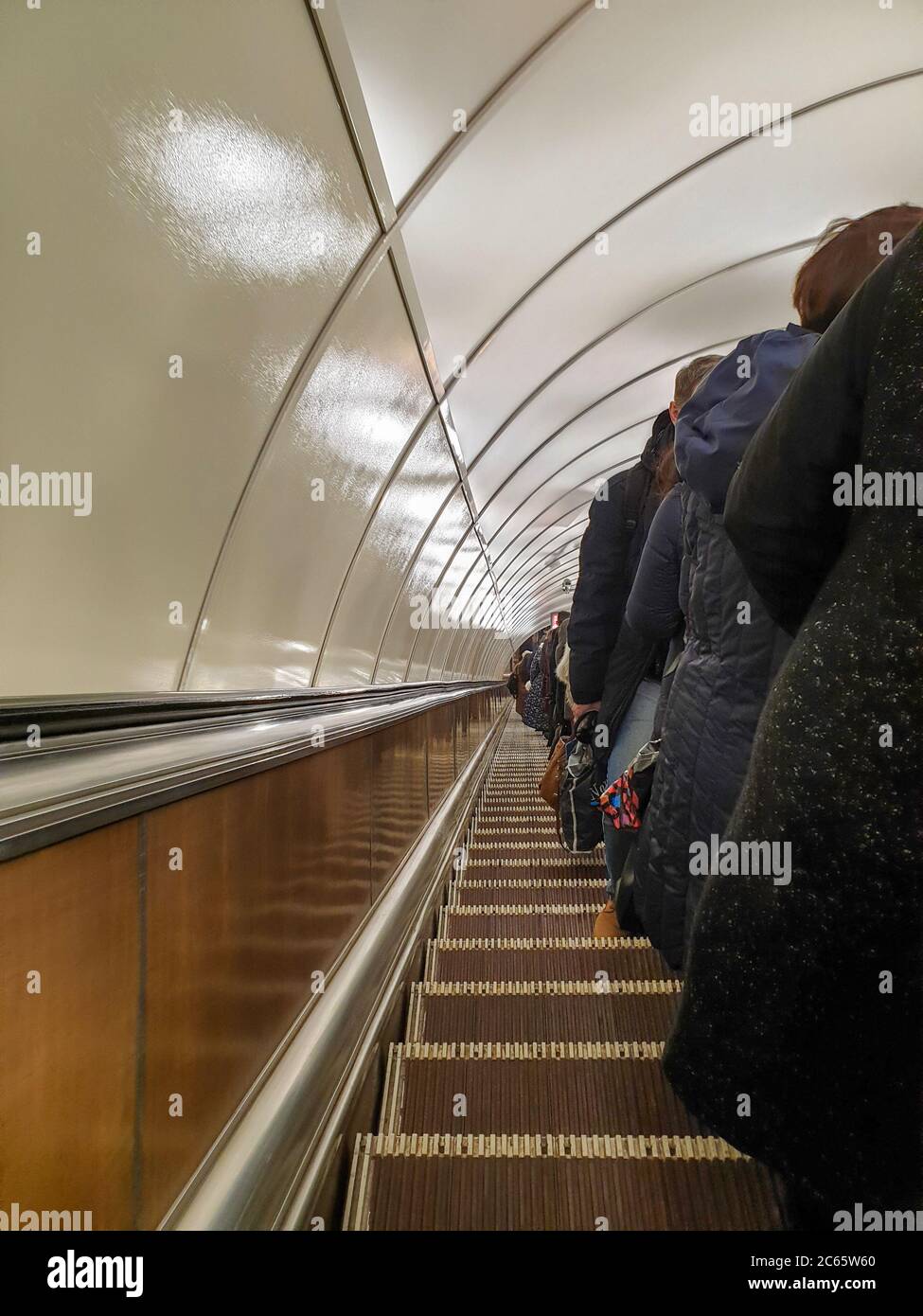 Les gens font un long escalier mécanique dans le métro. Banque D'Images