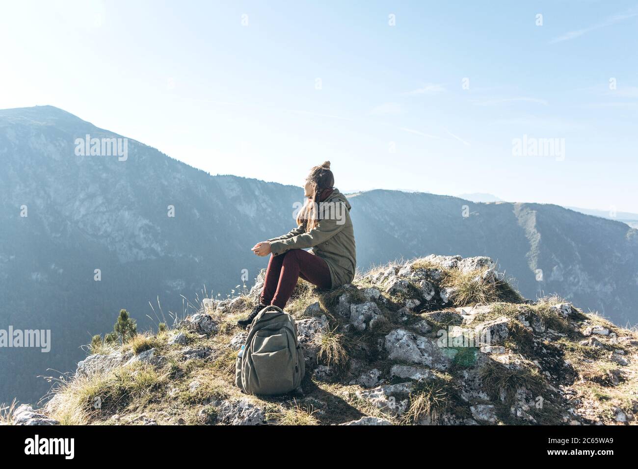 Une fille touriste ou voyageur assis sur un pic dans la solitude jouit de silence et de belles vues sur les montagnes. Banque D'Images