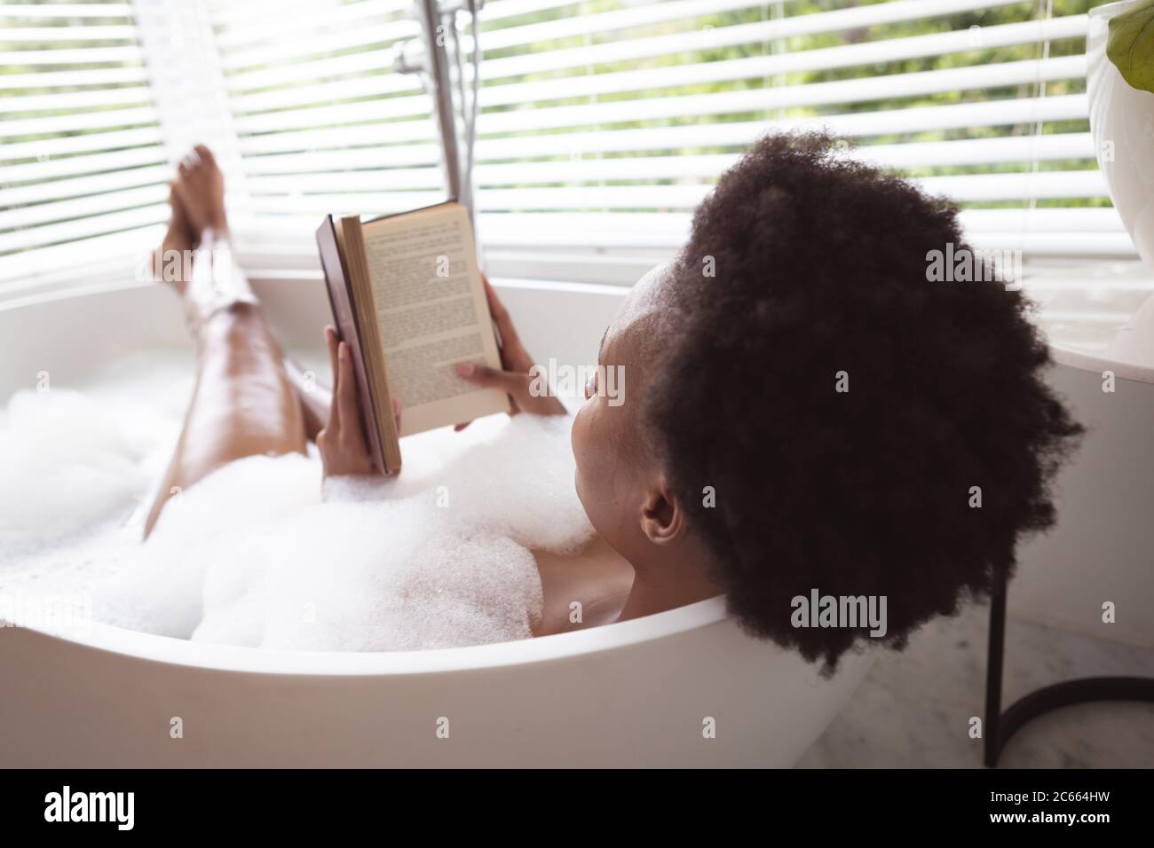 Femme lisant un livre dans une baignoire Banque D'Images