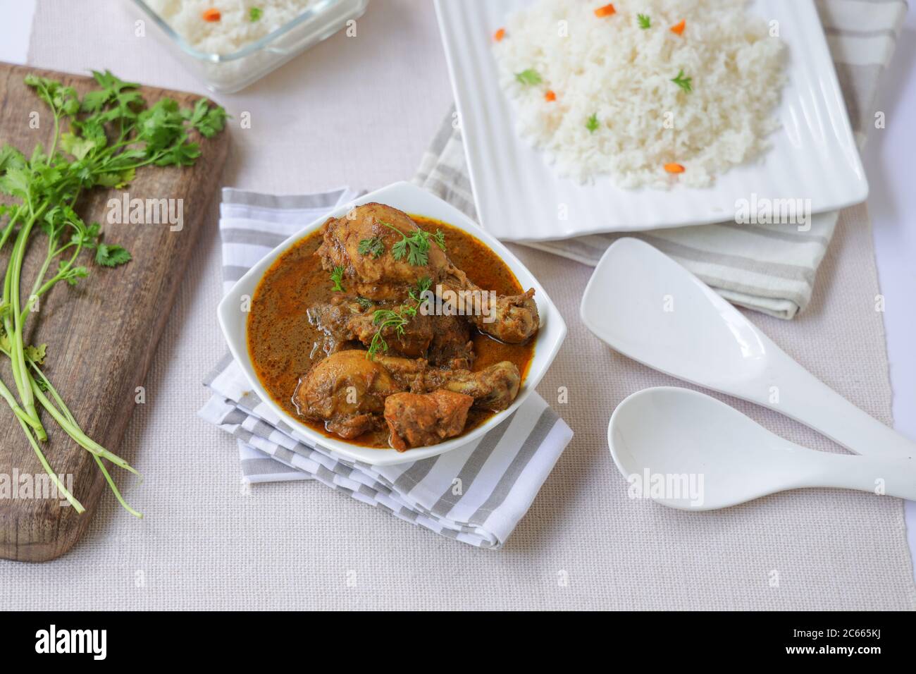 Cari de masala de poulet avec du riz ghee ou du riz biryani, placé dans un tachewares carré blanc avec de la menthe de coco verte chutne et raita Banque D'Images