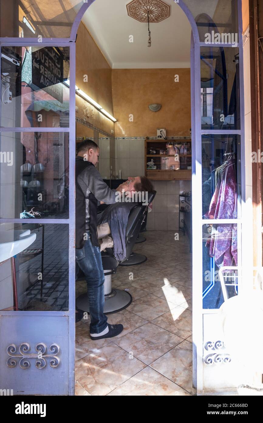 L'homme a un rasage par un barbier à Marrakech, au Maroc. Banque D'Images