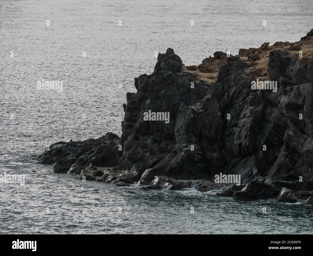 Rochers de roche de lave noire labouée par la mer Banque D'Images