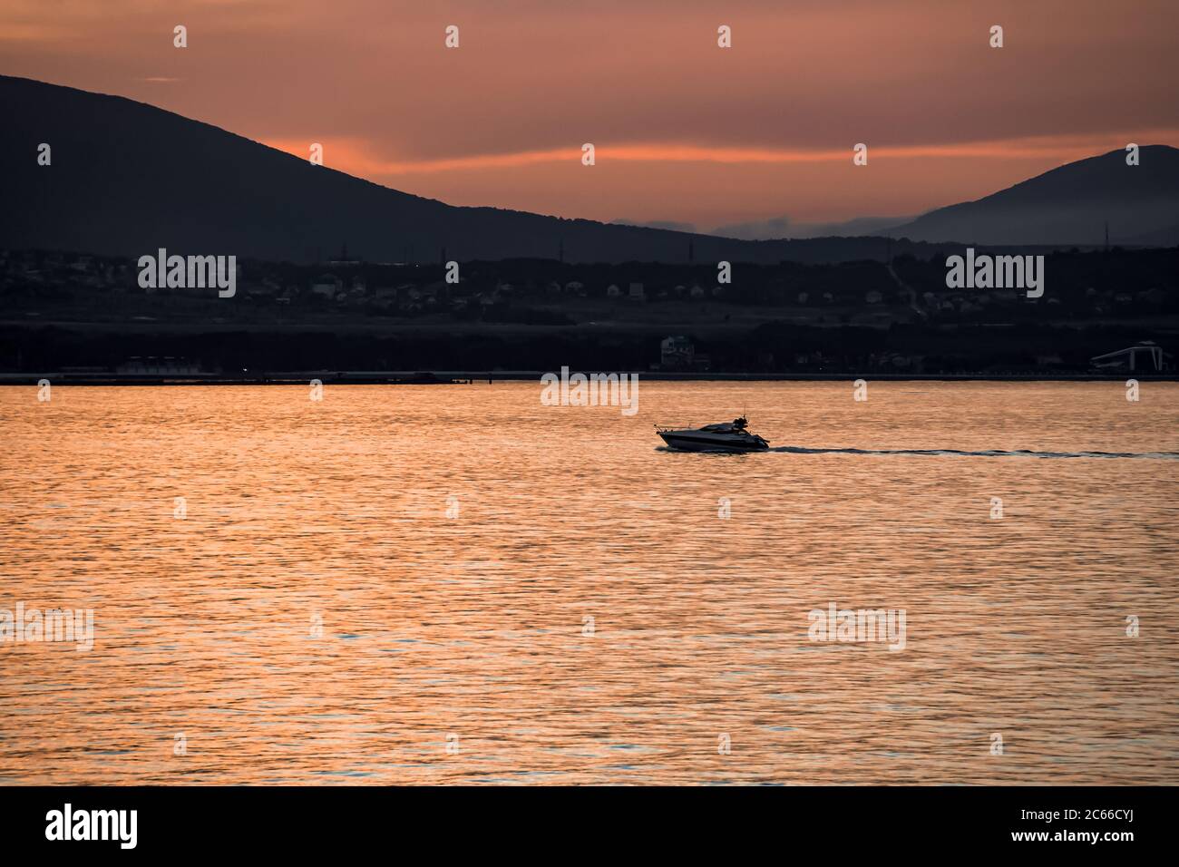 La côte et le paysage marin orange vif d'été au coucher du soleil, un yacht de plaisir sur fond des montagnes de la ville de la station balnéaire de Gelendzhik Banque D'Images