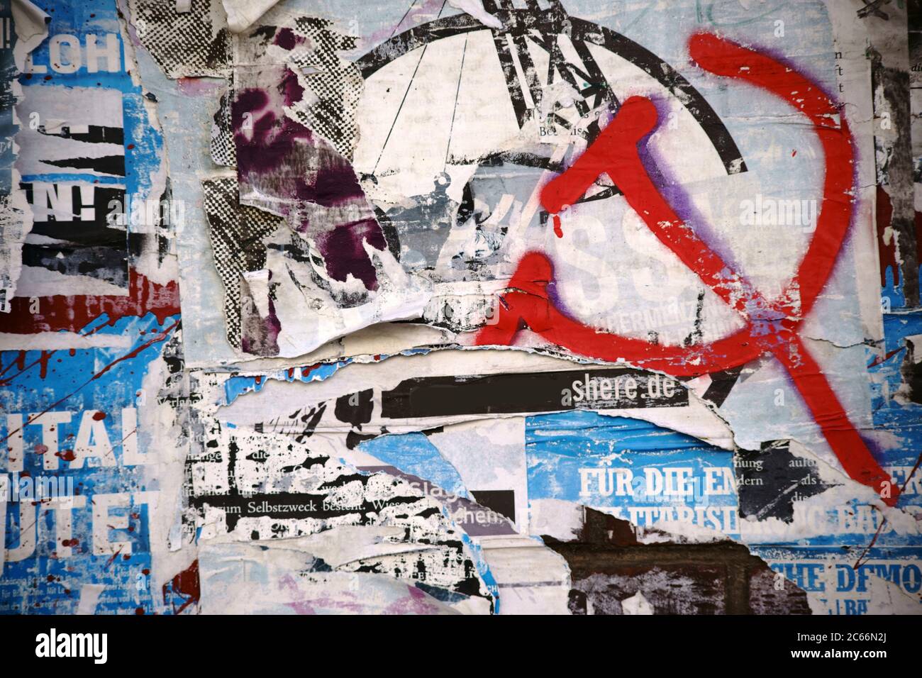 Gros plan d'un panneau publicitaire avec des morceaux de papier déchirés d'affiches et d'affiches publicitaires et pulvérisés sur le symbole de marteau et de faucille, Banque D'Images