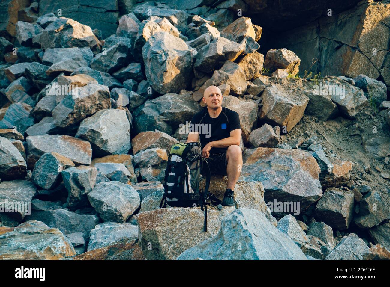 un voyageur repose sur une pierre et regarde le bord autour de lui. Un touriste se trouve sur le fond du rocher en été Banque D'Images