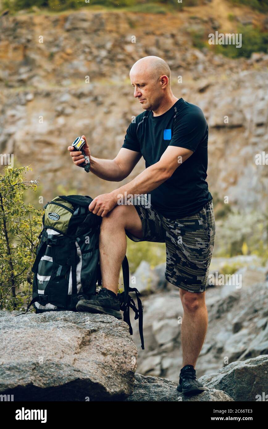 un voyageur regarde la boussole dans sa main et tient un sac à dos à côté de lui-même sur le fond des rochers Banque D'Images