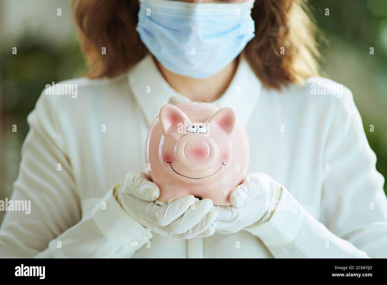 La vie durant la pandémie du coronavirus. Gros plan sur une femme en blouse blanche avec masque médical, banc de porc et gants. Banque D'Images