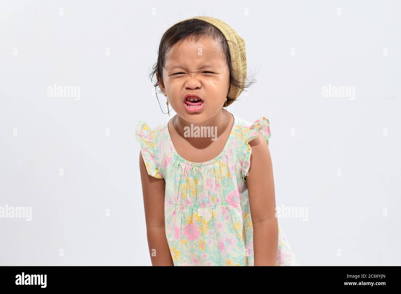 Petite fille a poussé sa bouche tout en fermant ses yeux, isolée sur blanc Banque D'Images