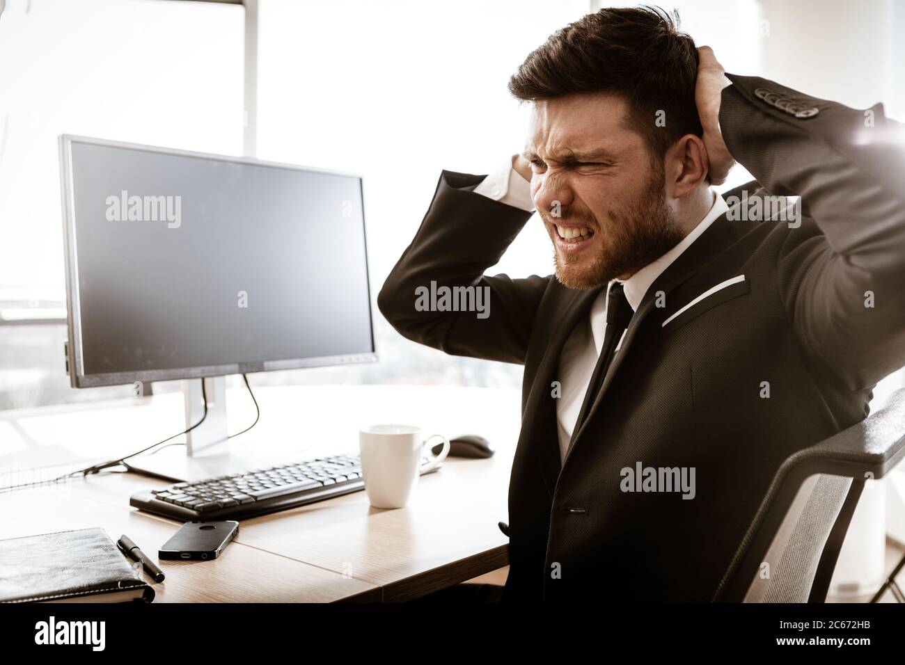 Concept de crise d'entreprise. Un jeune homme d'affaires émotionnel au travail. Inquiet, le responsable stressé assis à la table du bureau se déchire des cheveux avec les mains. Occupé Banque D'Images