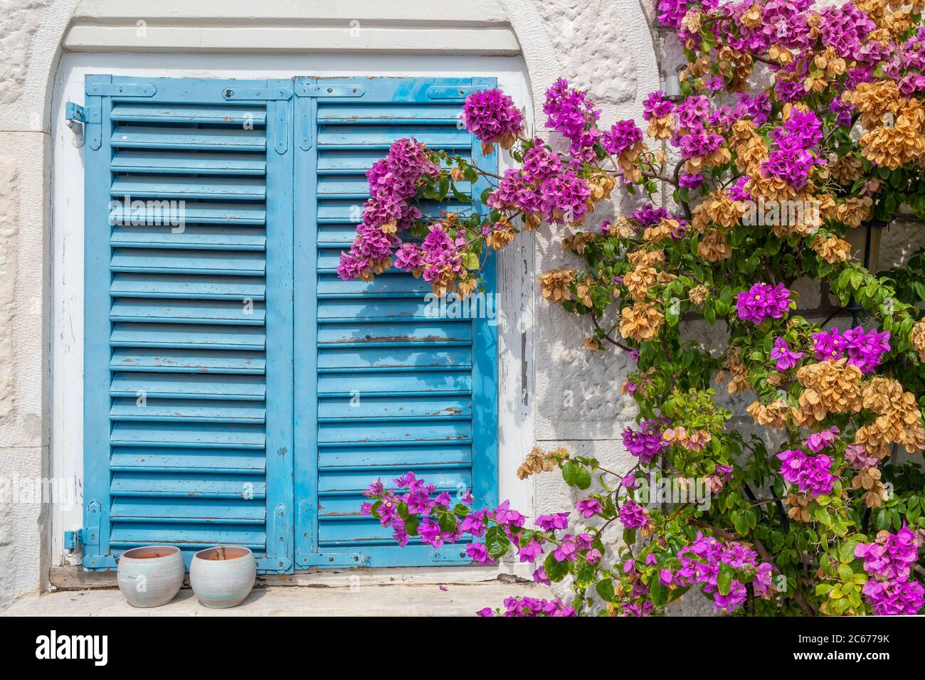 Maison méditerranéenne traditionnelle avec des volets bleus et des fleurs violettes Banque D'Images