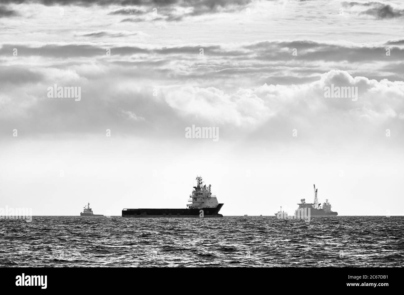 Image en noir et blanc des silhouettes des navires à l'horizon au coucher du soleil. Banque D'Images