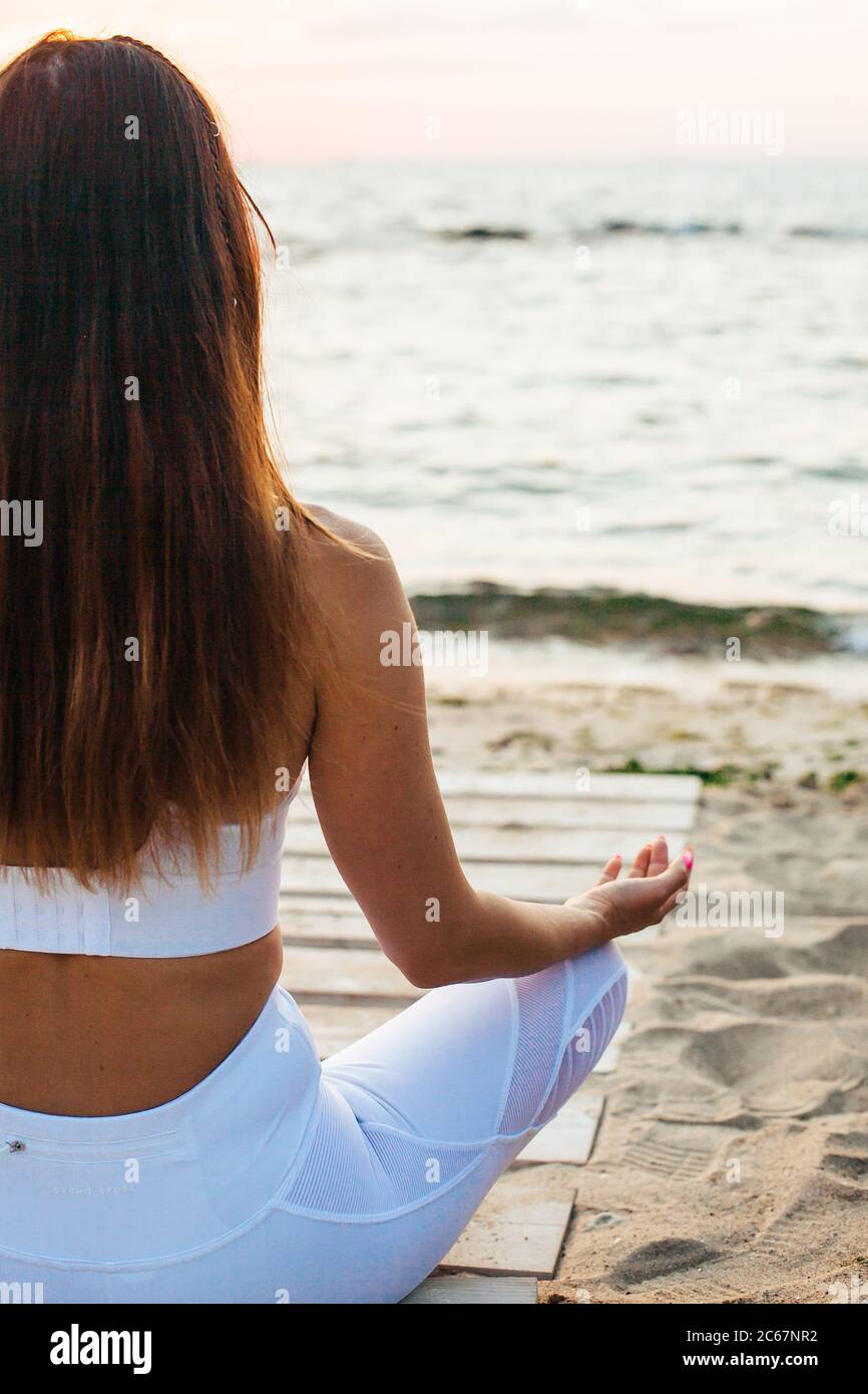 Vue latérale d'une jeune femme debout dans un poste de yoga Warrior sur une plage de sable Banque D'Images
